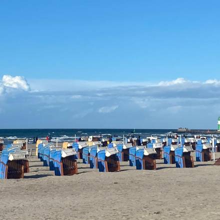Ostseestrand voll mit Strandkörben und im Hintergrund ist der Grüne Leuchtturm