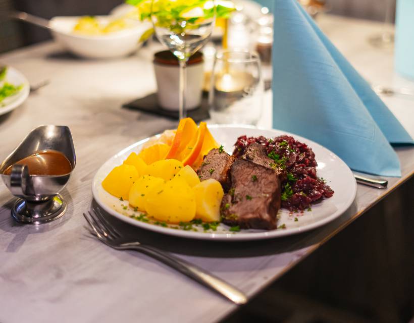 Braten mit Kartoffeln und Rotkraut auf einem gedeckten Tisch im Restaurant